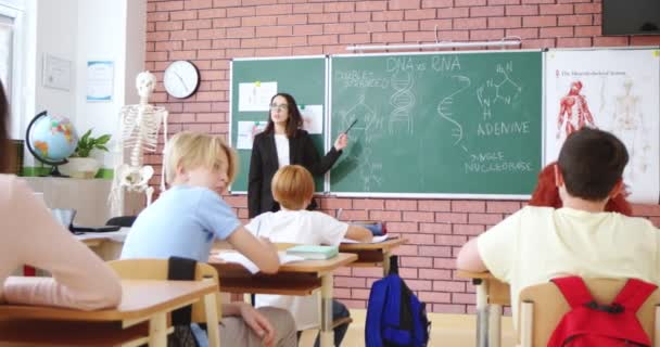 Beyaz Genç Güzel Bir Biyoloji Öğretmeni Sınıftaki Öğrencilere Dna Formüllerini — Stok video
