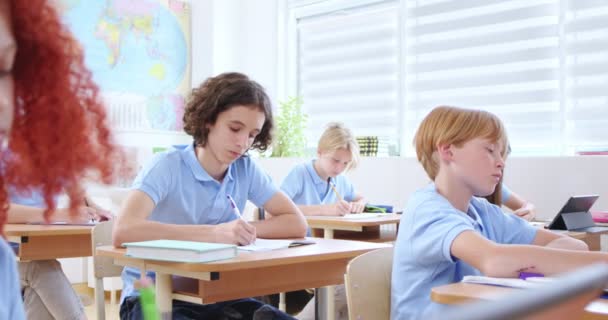 Uppmärksamma Barn Med Identiska Blå Shirts Som Sitter Vid Skrivbordet — Stockvideo