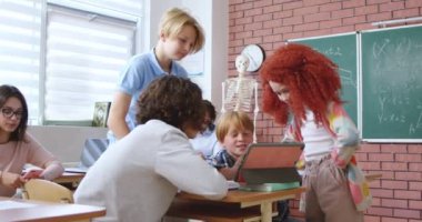 Okuldaki dijital tablet ekranda birlikte bakarken gülümseyen ve konuşan neşeli beyaz öğrenciler. Modern aletler kullanarak ders aralarında eğlenen mutlu çocuklar..