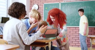 Kafkasyalı ergenler, akademisyenler ve liseli kızlar tablet cihazından bir şey izlerken masalarında oturup konuşuyorlar. Genç kızlar ve erkekler sohbet ediyor ve tatilde bilgisayar kullanıyorlar..
