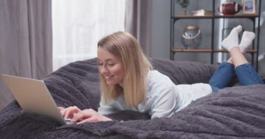 Bilgisayarında yazı yazan yetişkin bir kadının karnının üzerine uzanmış portresini yakından çek. Kadın, sosyal medyada bir zımbırtıda kayıyor ve gülüyor. İşten sonra bilgisayar başında dinlenen bir kadın..