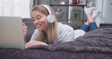 Kafkas kadının portresi. Dizüstü bilgisayarında yazarken karın üstü yatıyor. Müzik dinleyen ve kulaklıklara dokunan bir kadın. Alet üzerinde kadın sosyal medyada kaydırma ve dans hareketleri.