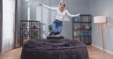 Genç, aktif, beyaz bir kadının koltukta zıplayıp sarılacağı bir fotoğraf. Mutlu, kaygısız insanlar konsepti. Yavaş çekim videosu.