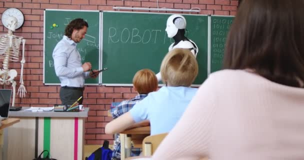Καυκάσιος Δάσκαλος Στέκεται Στον Μαυροπίνακα Και Δείχνει Ρομπότ Ανθρωποειδές Στην — Αρχείο Βίντεο