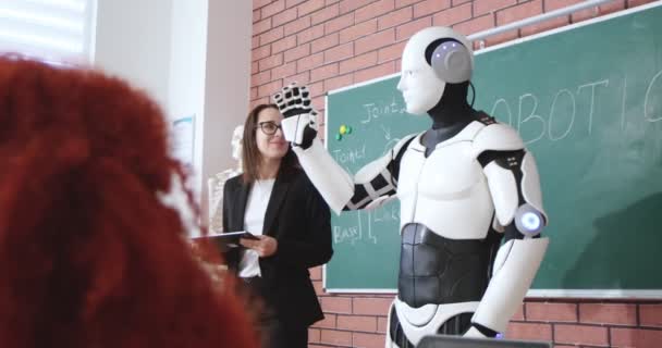 白人快乐的女教师站在黑板前 向小班学生展示机器人人形 在学校教机器人和技术 儿童教育 机器人用手挥手 — 图库视频影像