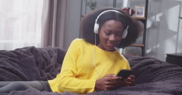 스마트 소파에 노란색 스웨터에 아프리카계 미국인 여성의 초상화를 닫습니다 헤드폰에 — 비디오