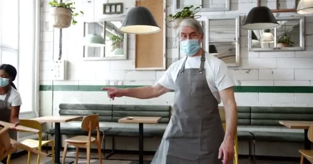 Seniorchef Maske Und Schürze Spaziert Café Zwischen Den Tischen Umher — Stockvideo