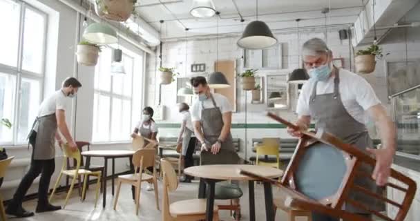Jonge Oudere Cafémedewerkers Grijze Schorten Medische Maskers Zetten Stoelen Houten — Stockvideo