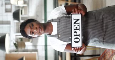 Kafe mutfağında duran ve kameraya kapalı masa gösterisi yapan güzel Afro-Amerikan bayan garsonun dikey portresi. Restoranın kadın şefi kapatıyor. Dikey.