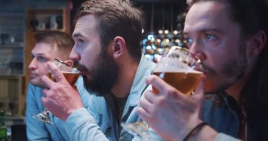 Bir grup genç adam barda takılıyor, bira içiyor ve televizyon yayınını tartışıyorlar. Üç arkadaş güzel bir konuşma yapıyor, gülümsüyor, başını sallıyor ve iyi vakit geçiriyor..