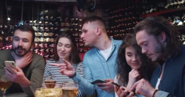 Kafkasyalı spor hayranları, geceleri barda bahisçilerin akıllı telefon reytinglerini merak edip kontrol ediyorlar. Erkek ve kadın arkadaşlar barda birlikte vakit geçiriyorlar ve cep telefonlarından spor maçı sonuçlarını izliyorlar..