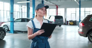 Şapkalı, üniformalı, evraklı, beyaz, güzel bir kadın. Otomobil servisinde çalışıyor. Garajda arabalarla çalışan kadın tamirci. Kız teknisyen.