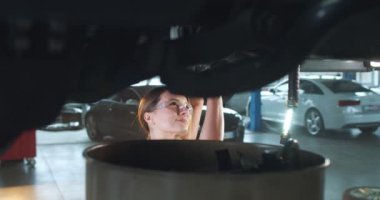 Araba altında duran beyaz kadın tamirci araba servisinde tamirle ilgili form dolduruyor. Motoru tamir ve kontrol için fatura yazan genç bir kadın. Garaj işi kavramı.