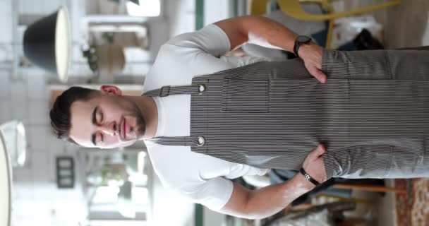 在围裙下 一位英俊的白人青年侍者站在咖啡馆厨房里 摆出一副相机的垂直肖像 垂直格式的图像 餐馆的男厨师 — 图库视频影像