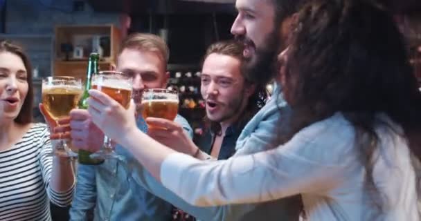 一群年轻的朋友在酒吧里聚会 碰碰玻璃杯和啤酒瓶 玩得很开心 微笑的男人和女人喝酒 说话和庆祝 — 图库视频影像