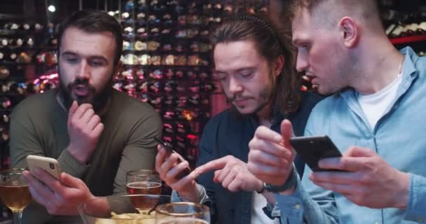 Grupa Młodych Mężczyzn Przesiaduje Barze Napięcie Sprawdza Telefony Ekran Telewizora — Wideo stockowe