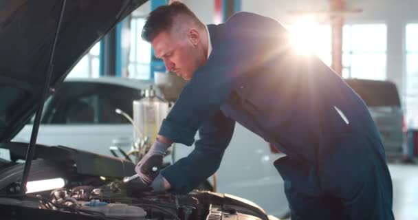 白人男性机修工在制服修理汽车发动机与汽车维修的沉船 年轻的工程师在大车库里修理发动机和拧扳手 维护概念 修理工作 — 图库视频影像