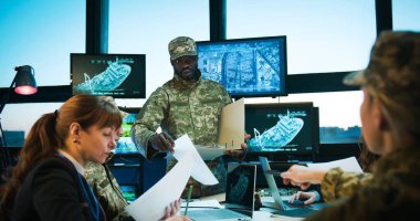 Genel karargah, Afrika kökenli Amerikalı bir adamın yüksek teknolojili ekranlar ve bilgisayarlarla yaptığı toplantıda askeri kararlar alıyor. Ordudaki çok ırklı erkek ve kadınlar.