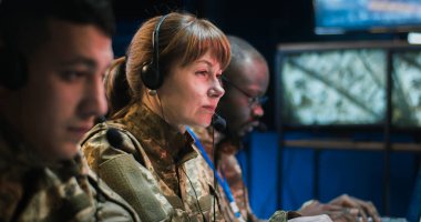 Kamuflaj üniformalı kadın ve erkek militarler ve operasyon ofisindeki bilgisayarlarda çalışan kulaklıklar. Orduya bilgi aktaran memurları kapatın..