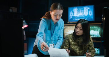 Beyaz bir kadın Asyalı kadın asyalı kadın askere bir şey gösteriyor ve onu ordu stratejisi konusunda eğitiyor. Kadınlar için eğitim askeri merkezi. Asker ve resmi tartışmalar