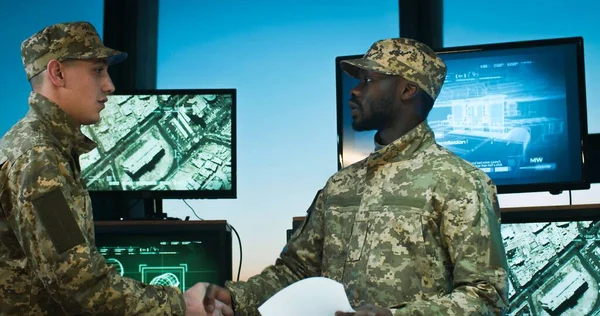 Beyaz ve Afro-Amerikan asker üniformalı askerler askeri ofiste karşılaşıp el sıkışıyorlar..