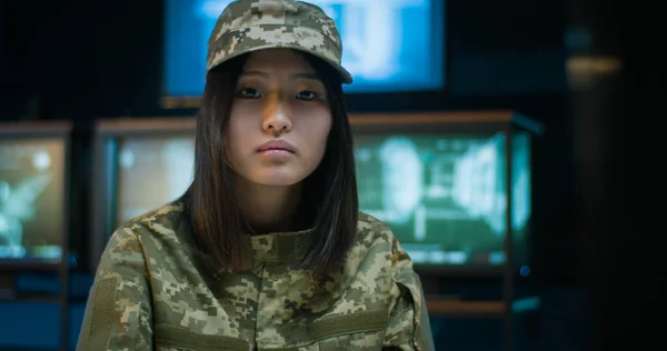 Portrait of female soldier in military data center. Asian young pretty woman wearing camouflage clothes sitting at laptop computer and working in army. Lady works in troop.