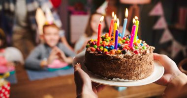 Rengarenk doğum günü pastasının kapağını kapatın. Anneleri mumları çocuklara getirirken..