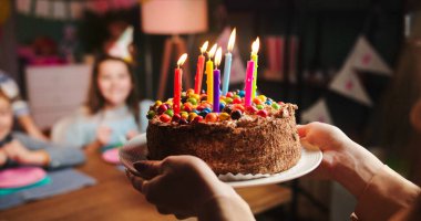 Doğum günü pastasını, doğum günü partisi için küçük şirin oğluna getirirken elinde mumlarla ve şekerlerle kapat..