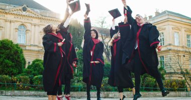 Melez ırklar genç ve mutlu yüksek lisans öğrencileri mezuniyet gününde eğleniyor, komik suratlarla dalga geçiyor, akademik şapkalarıyla gülüyor ve el sallıyorlar. Dışarıda..