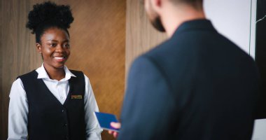 Lüks otellerde pasaport rezervasyonu yapan başarılı müşterilerin portresi. Misafirperver resepsiyonistin de yardımıyla. Güzel dost canlısı Afro-Amerikan otel yöneticisi.