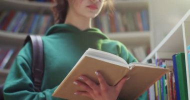 Beyaz tenli, gözlüklü, sayfaları çeviren, kitap okuyan ve kütüphanede bilgi arayan genç bir kız öğrenci. Edebiyat konsepti. Kitap raflarında ders kitabı olan kadın.