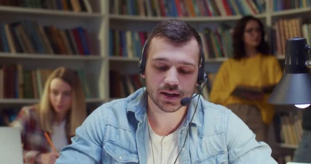 Běloch Sluchátkách Studuje Mluví Kamerou Dělá Poznámky Video Hovor Knihovně — Stock video