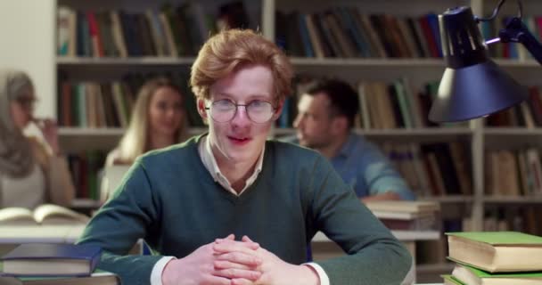Retrato Joven Alegre Estudiante Caucásico Gafas Sentado Mesa Biblioteca Sonriendo — Vídeos de Stock