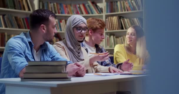 Веселые Молодые Смешанные Расы Мужчины Женщины Сидят Столом Библиотеке Разговаривают — стоковое видео