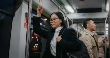 Asyalı kadın zor bir iş gününden sonra çok yorgun görünüyor. Olumlu ve memnun kalmaya çalışıyorum. Yaklaşan planları düşünüyorum. Metroyla ya da trenle eve dönerken pek çok şey düşündüm..