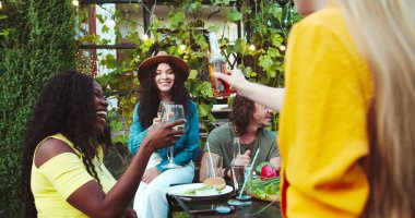 Bahçede içkilerle masada oturan çok ırklı neşeli bir genç. Afro-Amerikalı ve beyaz güzel kızlar dışarıda konuşuyor. Yakışıklı erkek ve Asyalı kız konuşuyor. Yaz partisi konsepti
