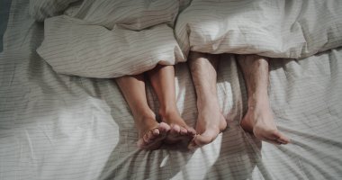 Neşeli bir ruh hali. Mutlu evli çiftlerin yatağında battaniyenin altında yatıp sabah uyandıklarında bacaklarıyla oynamalarını kapatın. Mutlu eşler birlikte mutlu tembel bir sabah geçirdiler.