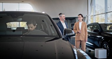 Müşteri konuşurken iki satış müdürü birbiriyle konuşuyor.