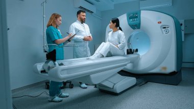 Beyaz önlüklü doktor MRI 'dan sonra hastaya tavsiye veriyor. Hasta MRI kapsülünde yatıyor. MRI dolabı. Modern ekipmanlar özel klinikte. Hemşire klasörü tutuyor ve not alıyor. MRI incelemesi.