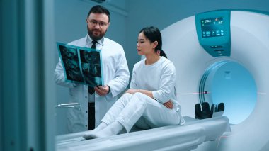 Doktor MR sonuçlarını hastaya gösteriyor. Doktor tomografi taraması yapıyor ve hastayla konuşuyor. Hasta tomografide oturuyor. Doktor tomografi görüntüsünü inceliyor. Manyetik rezonans prosedürü.