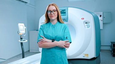 MRI makinesi. Bilgisayarlı tomografi ofisinin modern laboratuvar tıbbi asistanı modern ekipmanların arka planında kameraya bakıyor. Bilgisayar tomografi tarayıcısı, klinikteki teşhis odası.