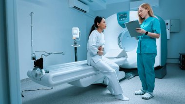 Modern klinikte biyopsi için röntgen bekleyen hasta. Tarayıcı masasında otururken doktoruna mide ağrısı şikayeti. MRI kapsülü ve klinikte yeni modern ekipmanlar.