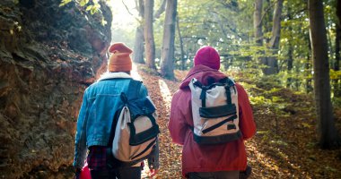 Sonbaharın ortasında yürüyüşe çıkan iki kişinin portresi. Sonbaharda orman doğasının güzelliğinin tadını çıkar. Sarı yapraklarla kaplı ormanda sabah yürüyüşü.