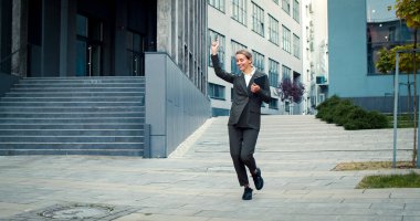Takım elbiseli mutlu iş kadını işe gidiyor. Güzel bir kadın işinden memnun. Kadın menajer mutlulukla dans eder..