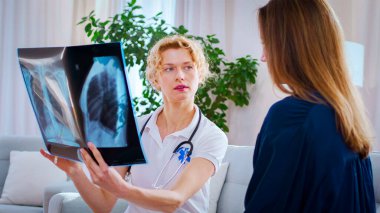 Doktorun hastaların röntgenlerini izlediği portre. Kadın aile doktorunu görmeye geldi. Hastanede günlük rutin.