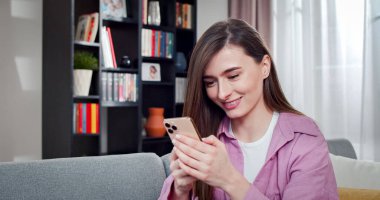 Odanın ortasındaki kanepede oturan beyaz kadın portresi, elinde bir alet tutuyor. Güzel bir kadın arkadaşlarıyla gülüyor..