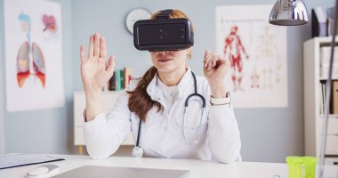 İş yerinde gözlük takan, boynunda steteskop olan beyaz kadın doktor portresi. Kadın yapay zeka aygıtı kullanarak elini kaldırıyor..