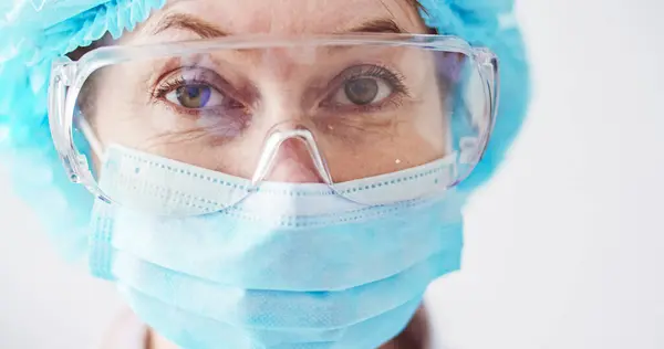 stock image Close up portrait of face of Caucasian female doctor wearing specialized clothes. Womans face with protective glasses and medical mask. Day routine in hospital.