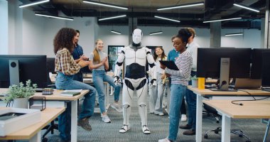 Robot odanın ortasında kalıyor. Çok ırklı iş arkadaşları el çırpıyor.