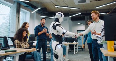 Yeni eserlerini büyük bir ofis odasının ortasında çevreleyen çok ırklı bir grup insan. Birlikte alkışlıyoruz. Erkeğe el sıkışmadan önce orta robot dansında. Kameraya başparmaklar gösteriliyor.